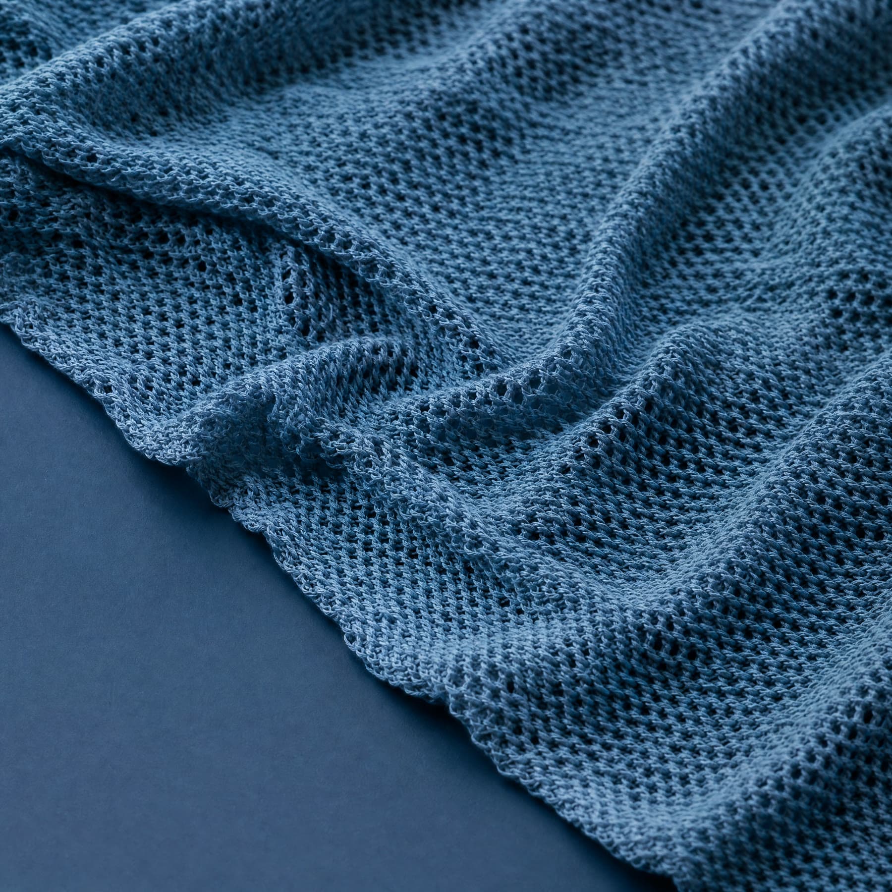 Extreme macro of an open, low-weight swim knit, the loops loose enough to see the airy structure of the fabric.